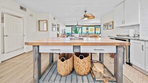 A spacious kitchen with a large island, white cabinetry, and a ceiling fan.