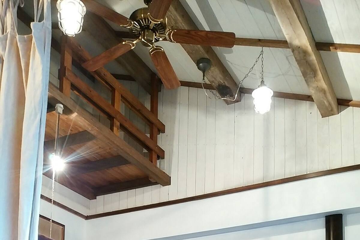 Una habitació d'estil dormitori amb llits superposats, bigues de fusta i un ventilador de sostre.