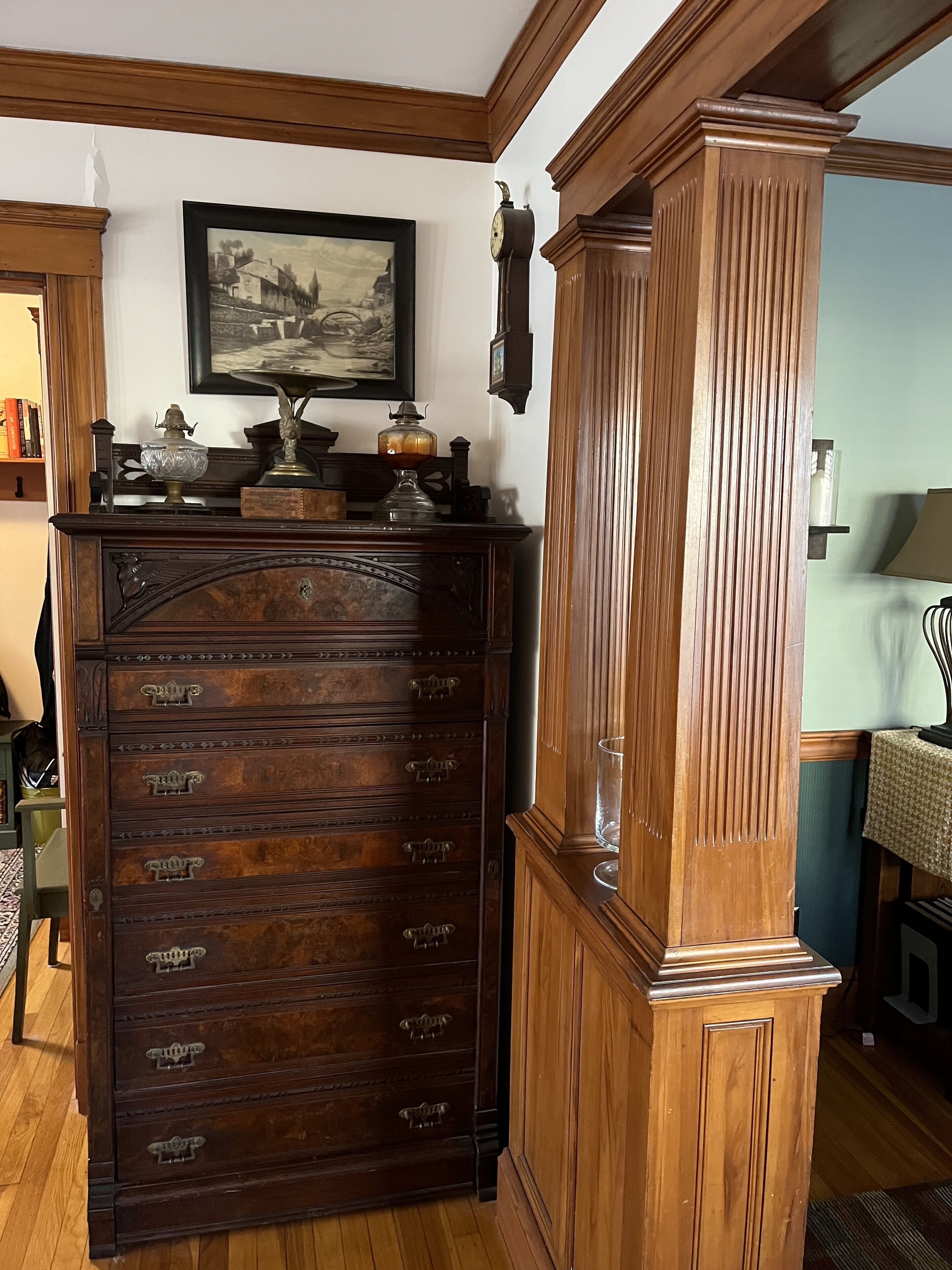 A wooden dresser with multiple drawers and a clock on top.