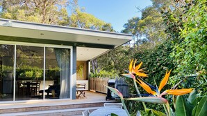 A modern house with a patio, a dining area, and a large window overlooking the garden. - Banksia Luxury Villa (Margaret River)