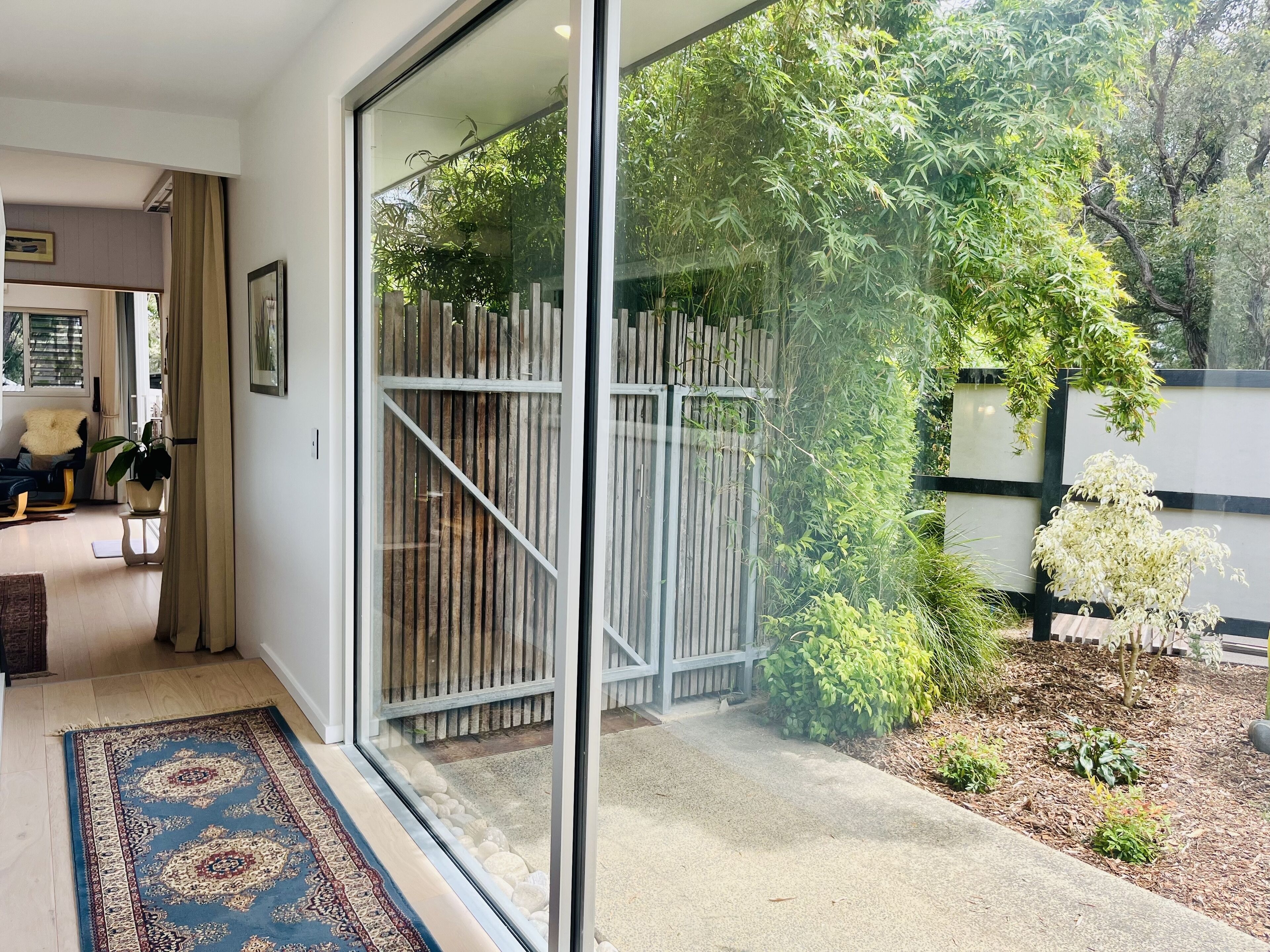 Un salon moderne doté d’une grande porte-fenêtre coulissante donnant sur un jardin.