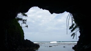 Une scène de plage, vue à travers l’entrée d’une grotte, avec des vagues qui déferlent sur le rivage.