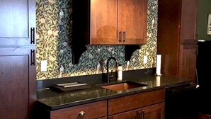 A kitchen with dark wooden cabinets, a black countertop, and a patterned backsplash. - 3500 SF Original School transformed into an artful,  gorgeous village home, yard (Bar Harbor)