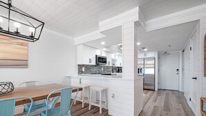 Moderni keittiö, jossa on valkoiset kaapit, kivestä tehty välitila ja sisäänrakennettu mikroaaltouuni.