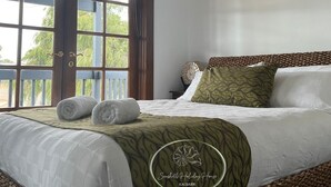 Une chambre d’hôtel avec un lit, une fenêtre donnant sur un beau paysage et un logo sur la couverture du lit.