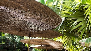 Gros plan sur la structure tressée d’un parasol, qui fait probablement partie d’un jardin ou d’un espace extérieur.