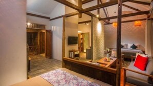 Une chambre d’hôtel moderne avec un grand miroir, un lit avec un oreiller rouge, une petite table avec des fruits et un téléviseur fixé au mur.