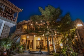 A courtyard with a wooden staircase, a statue, and potted plants. - Isann Villas (Siem Reap)