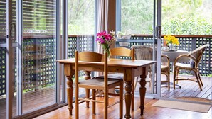 A wooden deck with a table and chairs, a glass door, and a view of greenery outside. - St Clair Cottage Peaceful romantic country getaway  (Margaret River)