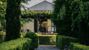 A pathway leading to a building with a covered pergola and a small tree in the center.