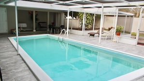 Une piscine rectangulaire dotée d’une plage blanche et d’un escalier en métal.