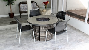 Une table ronde avec un plateau en verre et un socle en osier, entourée de quatre chaises noires.