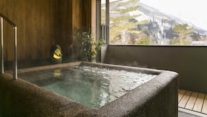 A hot tub with a view of a mountainous landscape through a large window. - Yado Kanzan (Minakami)