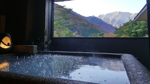 A hot tub with a view of mountains through a window. - Yado Kanzan (Minakami)