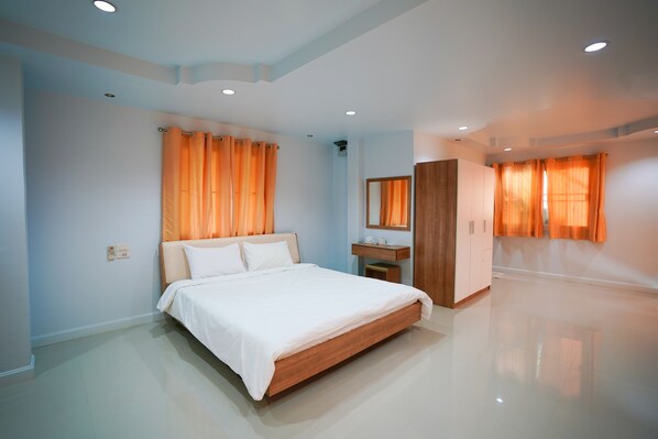 Un dormitorio moderno con una cama grande, un armario de madera, un tocador con espejo y cortinas naranjas.