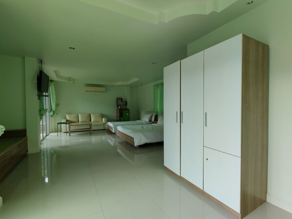 Amplia habitación de hotel con un armario grande, un sofá, una cama y un televisor.