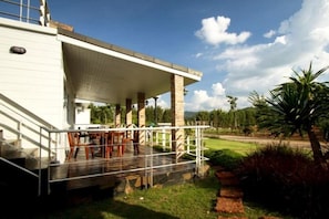 A covered outdoor area with a patio, stone columns, and a view of a grassy landscape.