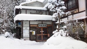Ein traditionelles japanisches Gebäude mit verschneitem Eingang und Beschilderung.