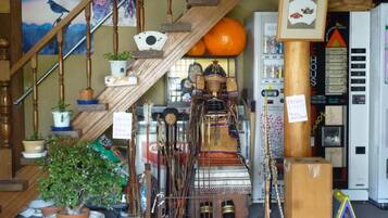 A staircase with wooden railings, a sign for Nagano 1998, and various items including a large orange, a vending machine, and a display of traditional Japanese artifacts.