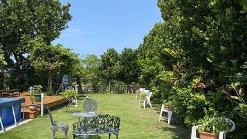 A well-maintained garden with a metal table and chairs, a small pool, and various plants.