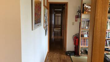 A hallway with wooden flooring, a fire extinguisher, and a bookshelf filled with books.