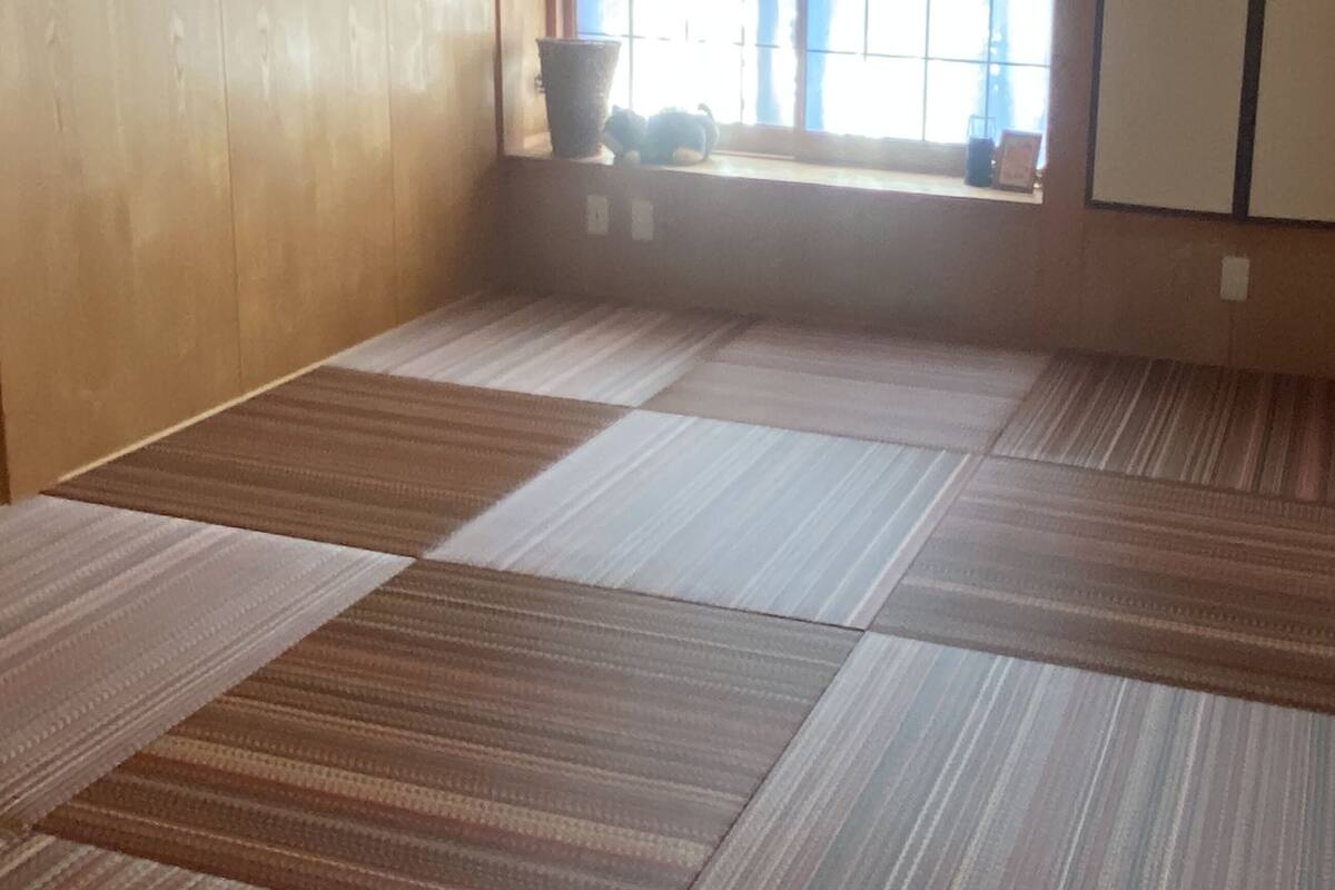 A room with tatami mat flooring, a window with a view, and a wardrobe.