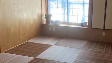 A room with tatami mat flooring, a window with a view, and a wardrobe.