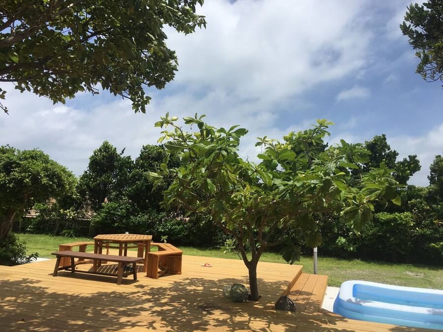 A wooden deck with picnic tables and a small inflatable pool.