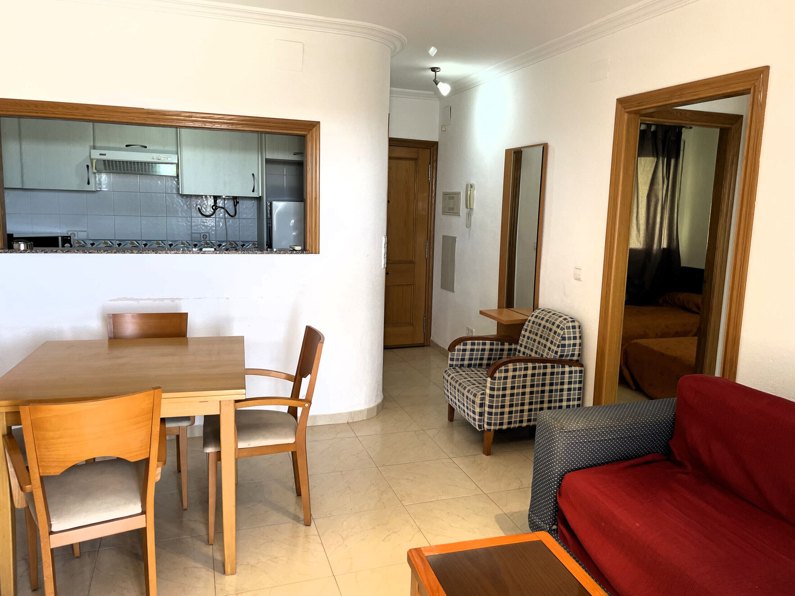 Un espace de vie compact comprenant un coin repas, une kitchenette, un canapé et un fauteuil.