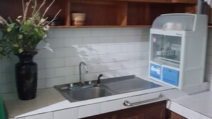 A kitchen with wooden cabinets, a sink, and a water dispenser. - Desiree's Lodge And Transient House, Baler Aurora (Baler)