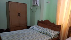 A single bed with a wooden headboard and striped bedding, a wooden wardrobe, and a wall-mounted air conditioning unit. - Desiree's Lodge And Transient House, Baler Aurora (Baler)