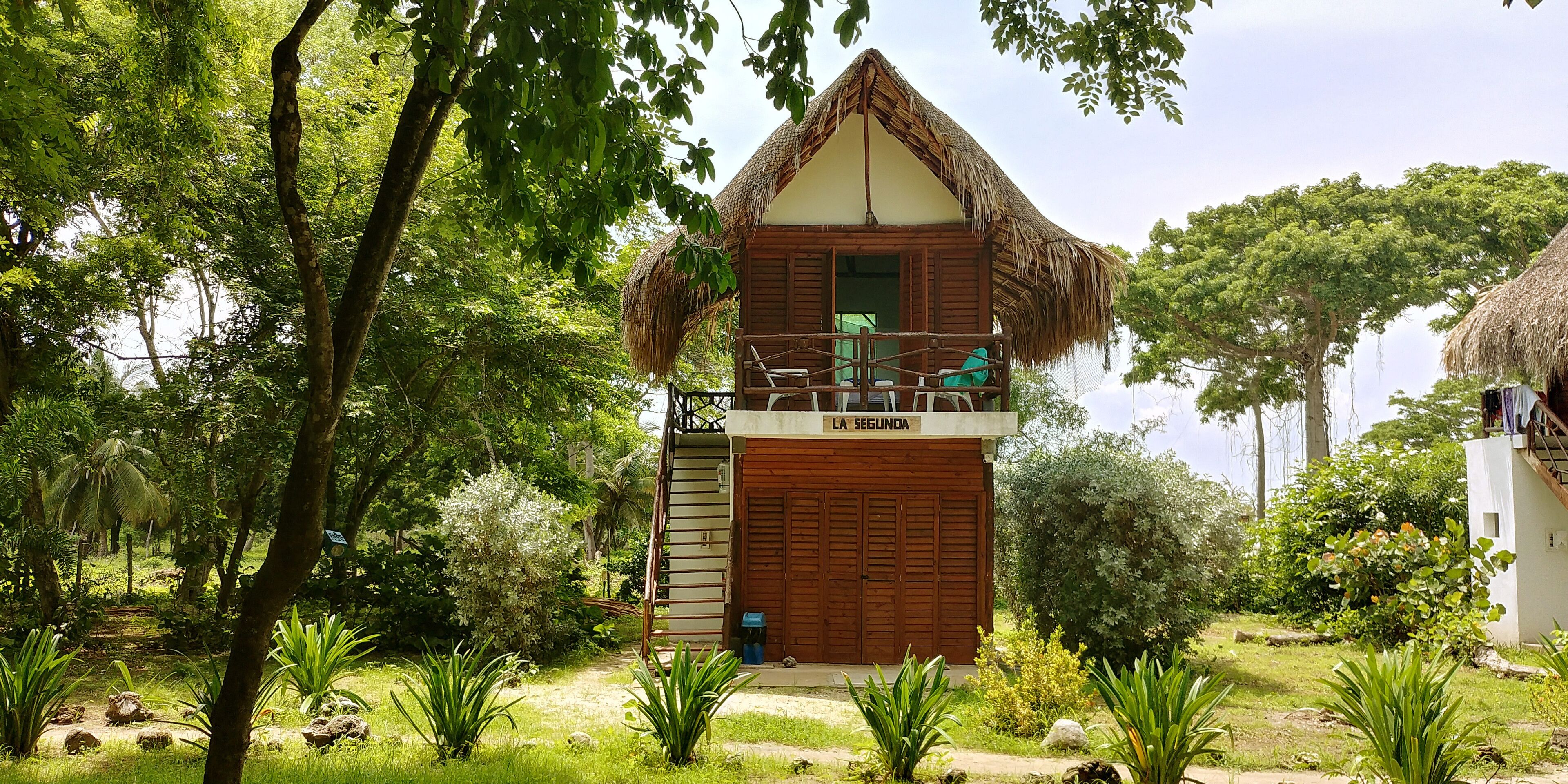 Una casa de madera con techo de paja, un balcón y un letrero que dice "LA SEGUNDA".