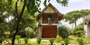 A wooden house with a thatched roof, a balcony, and a sign reading "LA SEGUNDA".