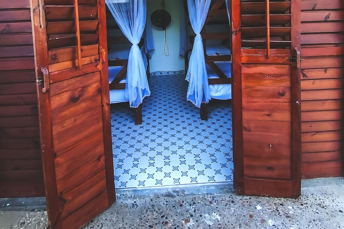Une cabane en bois avec un lit simple et un petit luminaire suspendu.