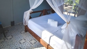 Une chambre avec un lit recouvert d’une moustiquaire, un ventilateur de plafond et des carreaux de sol décorés.
