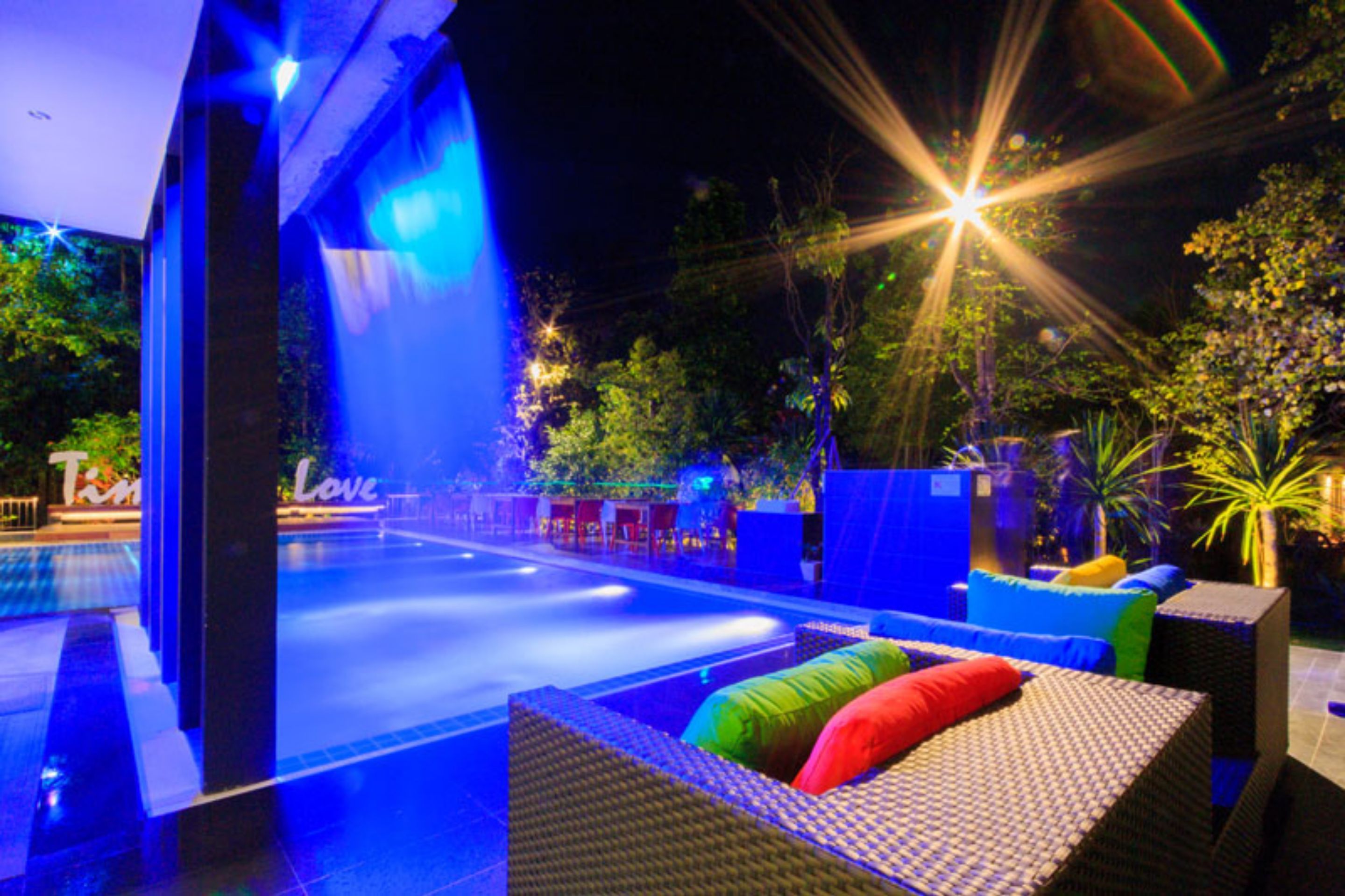 Un espace extérieur avec piscine, agrémenté d’un élément décoratif aquatique, de sièges et d’un éclairage décoratif.