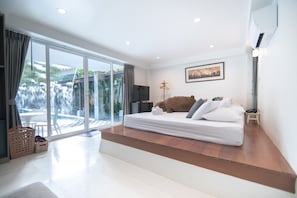 Quarto com uma cama grande, televisão e vista para uma cascata.
