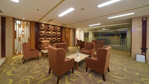 A hotel lobby with a patterned carpet, multiple seating areas, and a decorative wall. - Ayola Sentosa Palembang (Palembang)