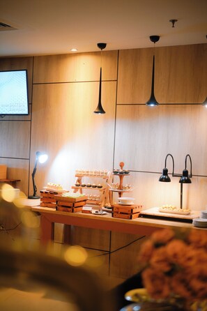 Cucina moderna con mobili in legno, luci a sospensione e un'area buffet con diversi piatti.