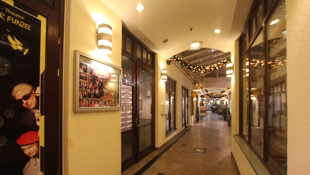 A corridor with framed pictures on the walls, a ceiling with lights, and a long hallway with doors on one side. - DRUSCHBA Boutique Apartment (Leipzig)