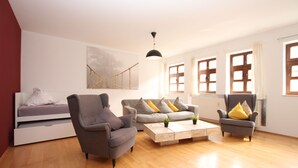 A modern living room with a sofa, armchairs, a coffee table, and a bed. - DRUSCHBA Boutique Apartment (Leipzig)