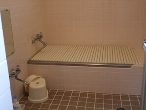 Une petite salle de bain comprenant des toilettes, un bidet et un espace douche doté d’un sol à lattes.