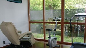 Un gimnasio en casa con una bicicleta estática, una silla de masajes y una cinta de correr.