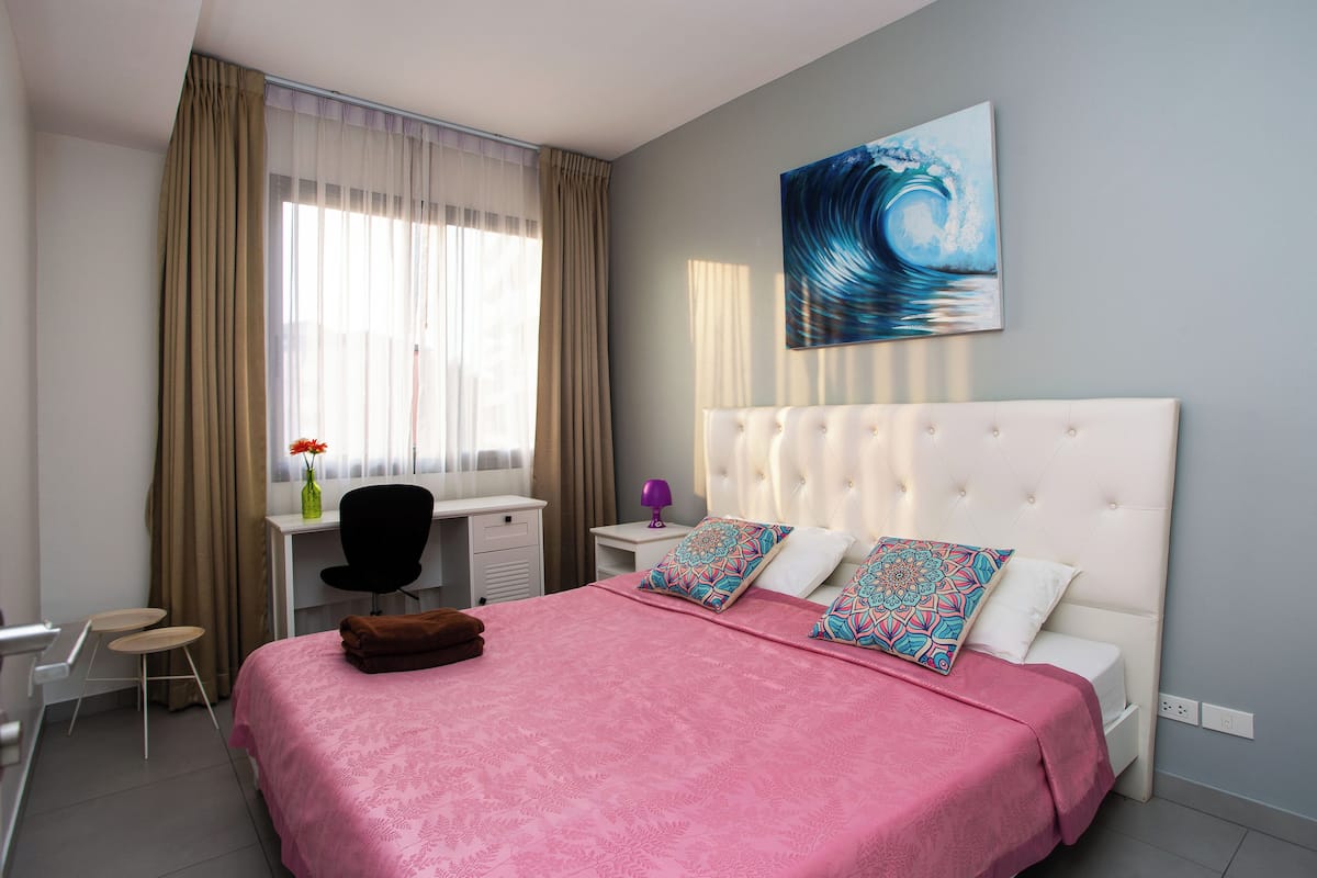 A modern bedroom with a large bed, a desk, and a chair.