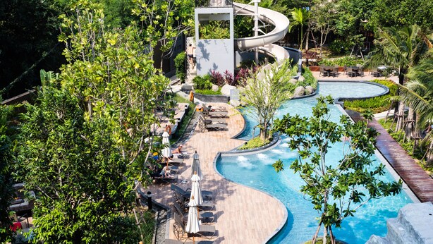 A resort with a winding pool, lounge chairs, and a water slide. - Unixx South Pattaya by GrandisVillas (Pattaya)