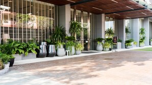 A modern building entrance with large windows, potted plants, and a tiled walkway. - Unixx South Pattaya by GrandisVillas (Pattaya)