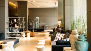 A modern interior with a sofa, white coffee tables, and a large vase. - Unixx South Pattaya by GrandisVillas (Pattaya)