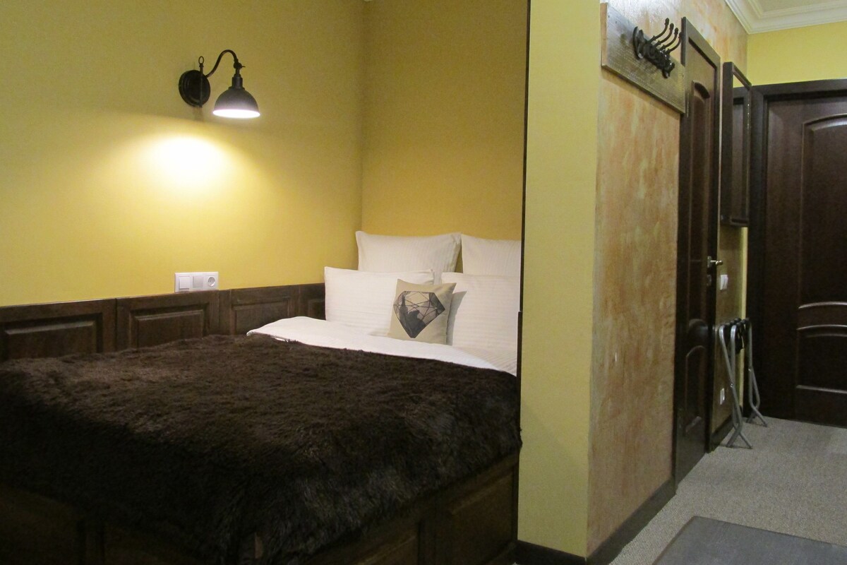 Un dormitorio con una cama, una mesita de noche, una lámpara de pared y una puerta.