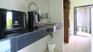 Eine kleine Küche mit einer schwarzen Electrolux-Mikrowelle, einem Wasserkocher und einem Geschirrständer.