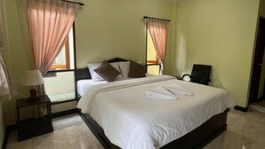A neatly arranged bedroom with a large bed, two bedside tables, a nightstand, and a chair. - Ron's Bungalow (Choeng Thale)